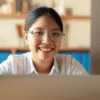 A smiling young Indian woman looking confidently at a laptop screen, suggesting the excitement of starting an online business.