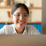 A smiling young Indian woman looking confidently at a laptop screen, suggesting the excitement of starting an online business.